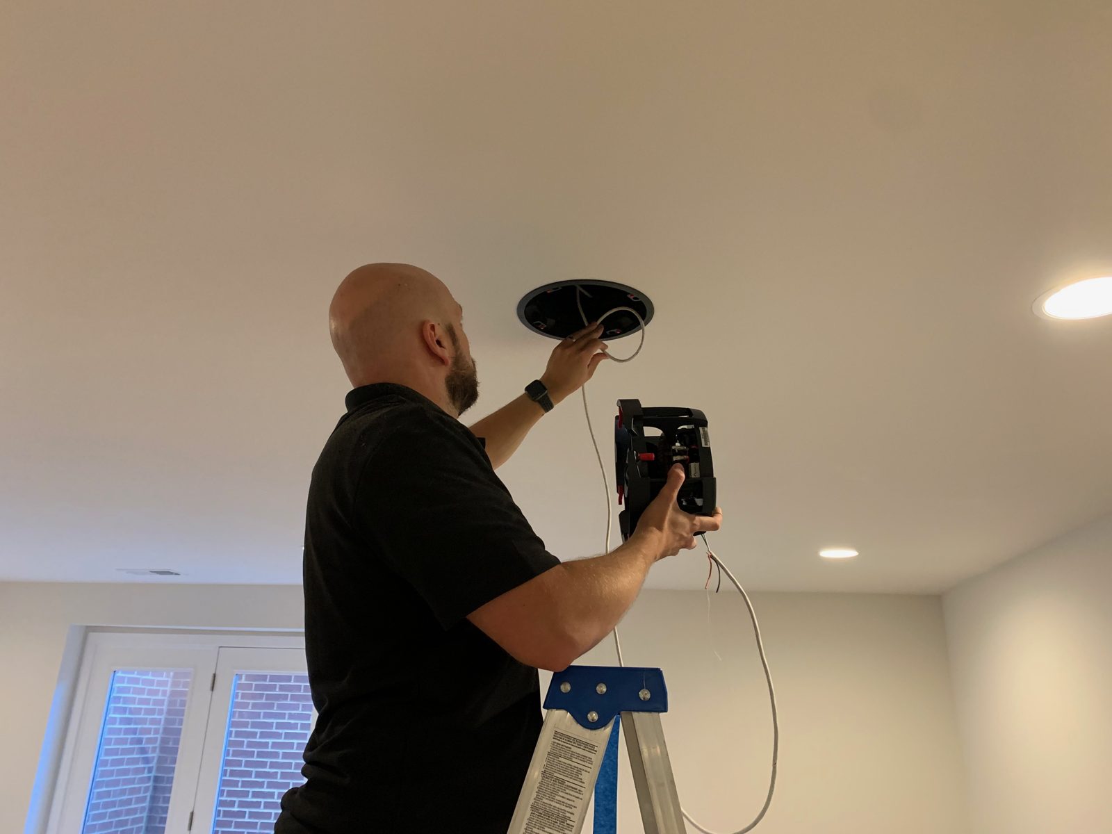 Brian on a ladder installing an in-ceiling speaker