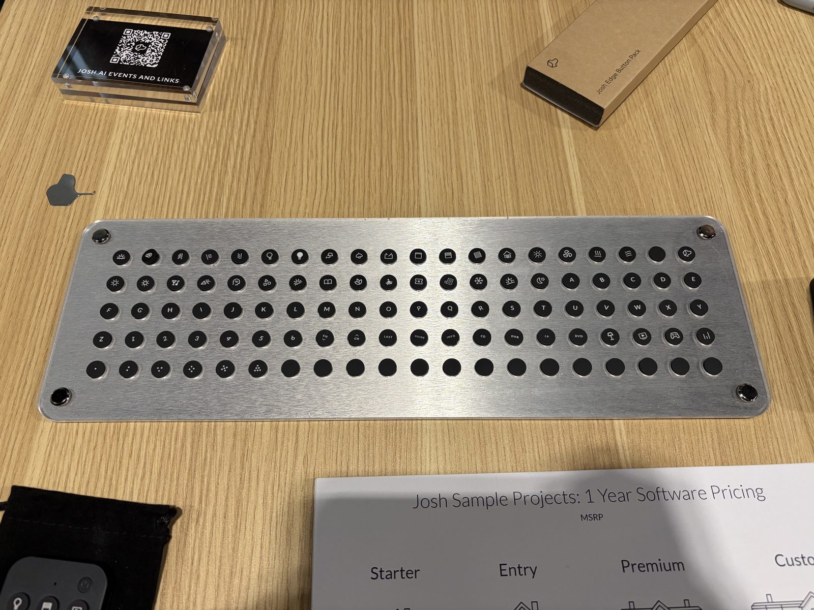 An aluminum tray holding about 100 black Josh Edge button caps printed with icons, letters, numbers and media labels, on a booth table at CEDIA Expo